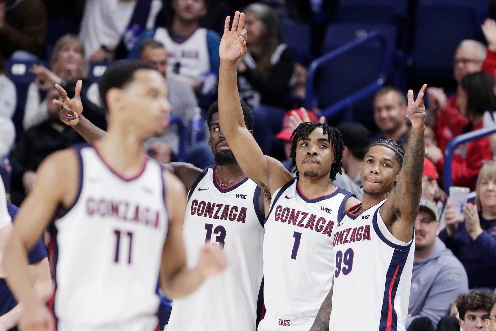 Gonzaga forward Graham Ike (13) along with guards Michael Ajayi (1) and Khalif Battle (99) gesture after a 3-point basket by Nolan Hickman (11) during the second half of an NCAA college basketball game against Bucknell, Saturday, Dec. 21, 2024, in Spokane, Wash. (AP Photo/Young Kwak)