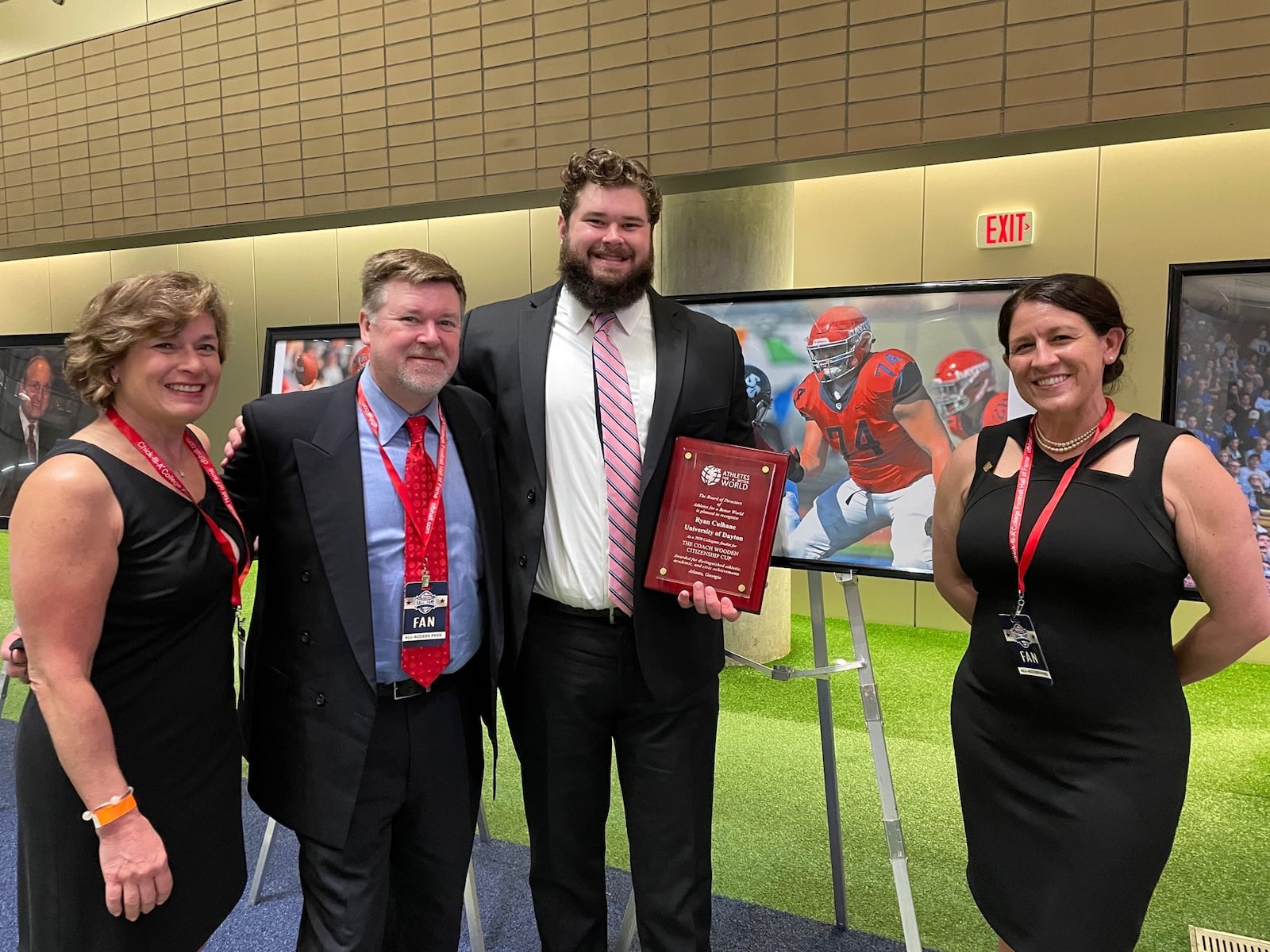 One of the four college finalists for the prestigious John Wooden Citizenship Cup given to the nation’s most outstanding role models among high school, college and pro athletes, former Dayton Flyers football lineman Ryan Culhane was honored last Thursday night at the College Football Hall of Fame in downtown Atlanta. He is pictured here at the College Football Hall of Fame in Atlanta in front of a photograph of him ( No. 74) in action during a Flyers game. With him are his mom Molly (left), dad Jim and UD Associate Athletics Director Krystal Warren (on right), who nominated him for the award. CONTRIBUTED