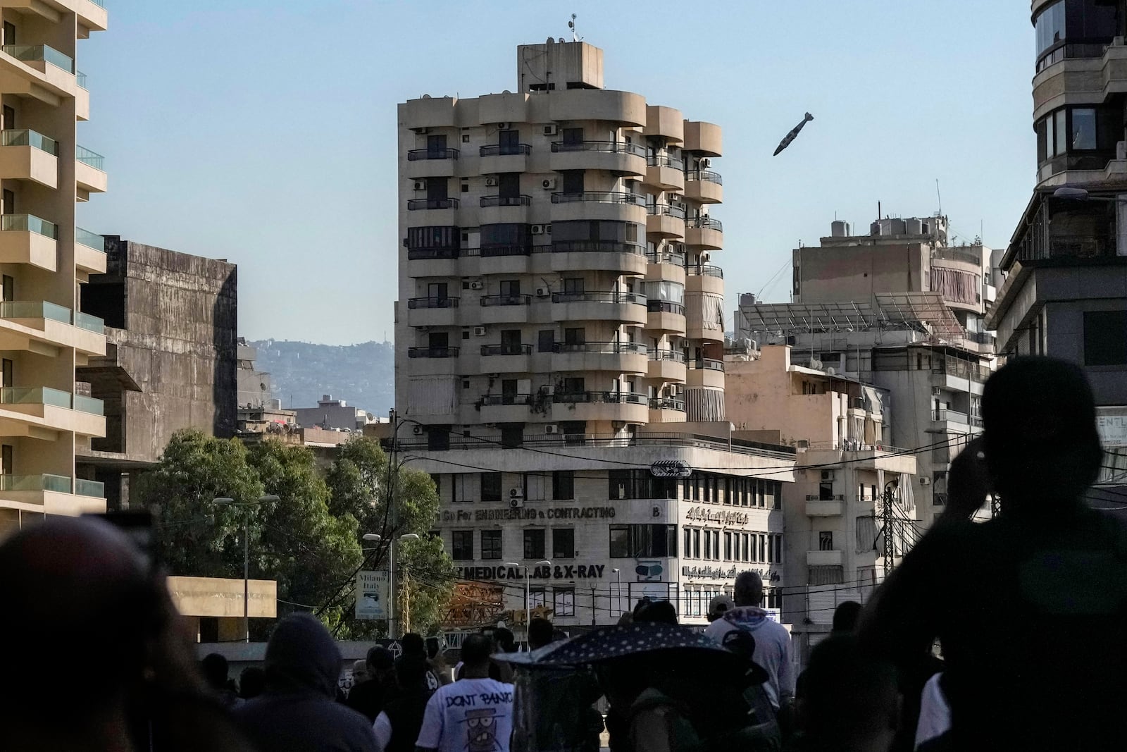 People look as a munition launched by Israeli forces makes its way to hit a building in Chiyah, in the southern suburb of Beirut, Lebanon, Friday, Nov. 22, 2024. (AP Photo/Bilal Hussein)