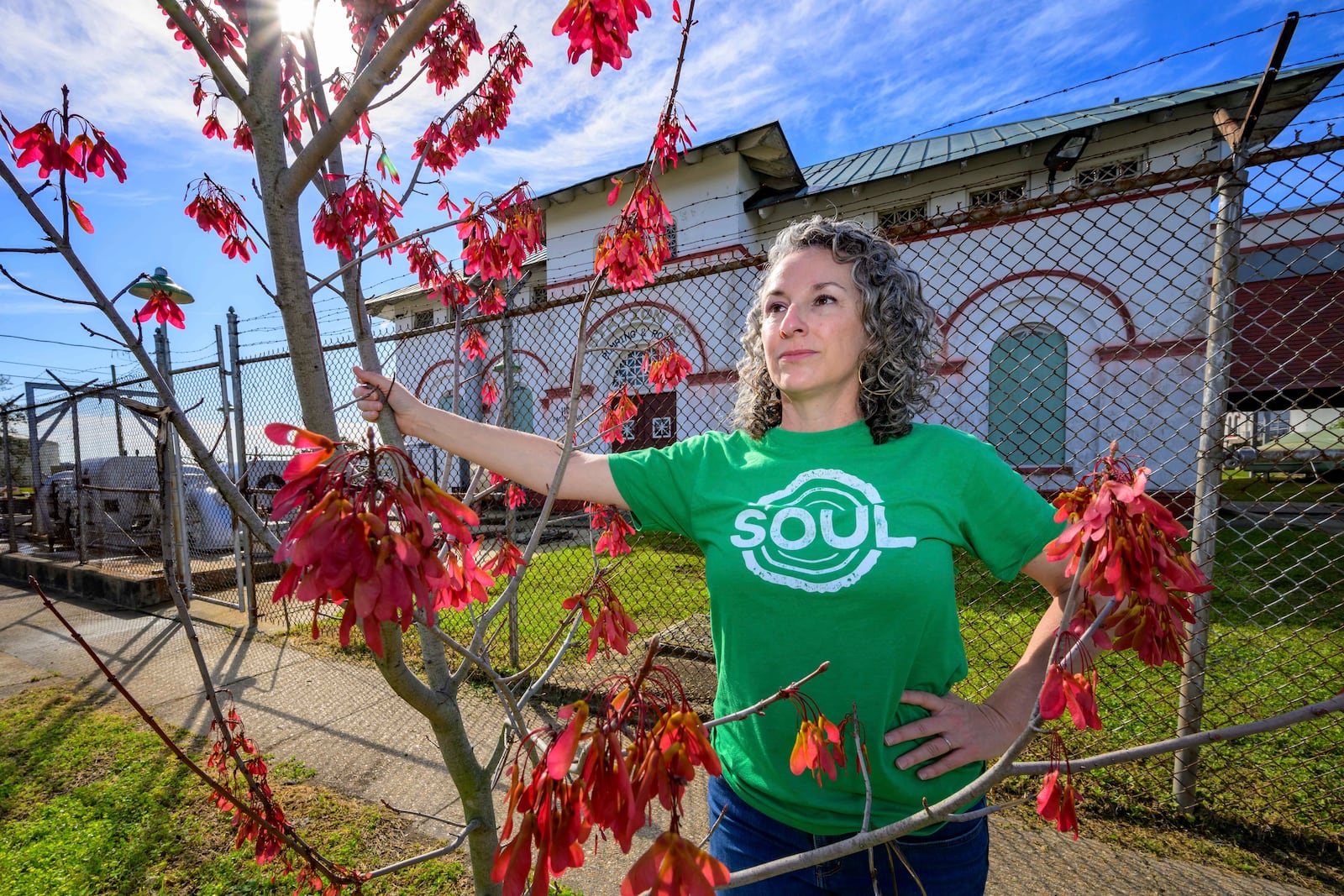 Susannah Burley, founding director of SOUL (Sustaining Our Urban Landscape), stands by a tree the organization previously planted in front of New Orleans Sewerage and Water Board pumping station in the Algiers neighborhood of New Orleans, Thursday, Feb. 27, 2025. (AP Photo/Matthew Hinton)