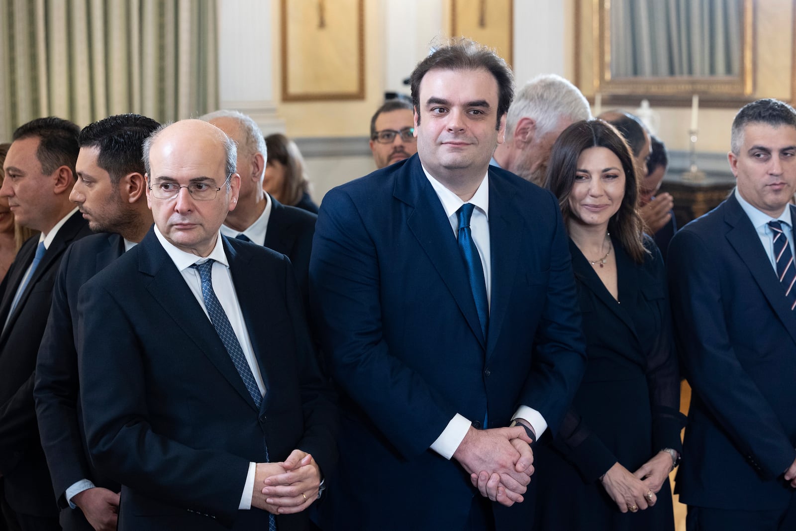 Newly appointed Finance Minister Kyriakos Pierrakakis, centre, stands between Deputy Prime Minister Kostis Hatzidakis, left, and Minister of Education Sofia Zacharaki, during a swearing in ceremony at the Presidential palace, in Athens, Greece, Saturday, March 15, 2025. (AP Photo/Yorgos Karahalis)