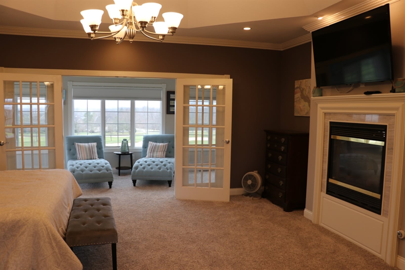 A deep tray ceiling gives the master bedroom suite an open feel and oversized French doors open out to a sunroom that looks out over the fairway. 