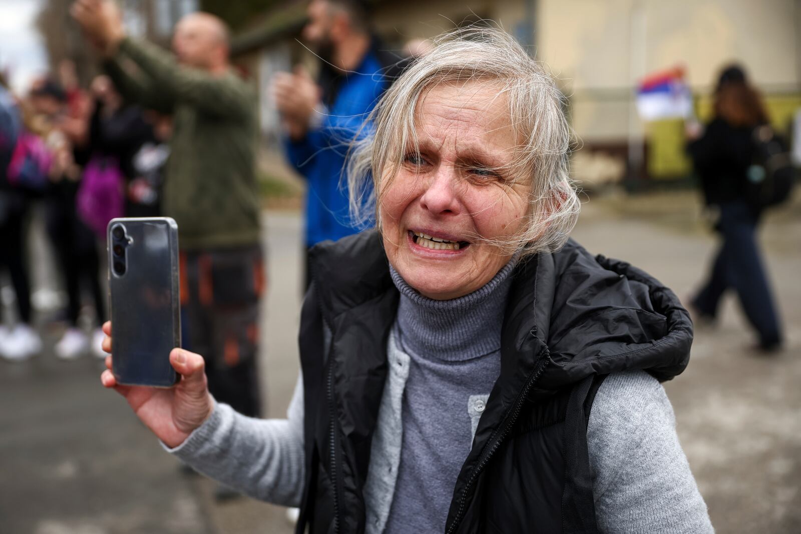 A woman cries and shouts as students and anti-government protesters pass trough her village as they march to Belgrade for a joint protest in Nova Pazova, Serbia, Friday, March 14, 2025. (AP Photo/Armin Durgut)