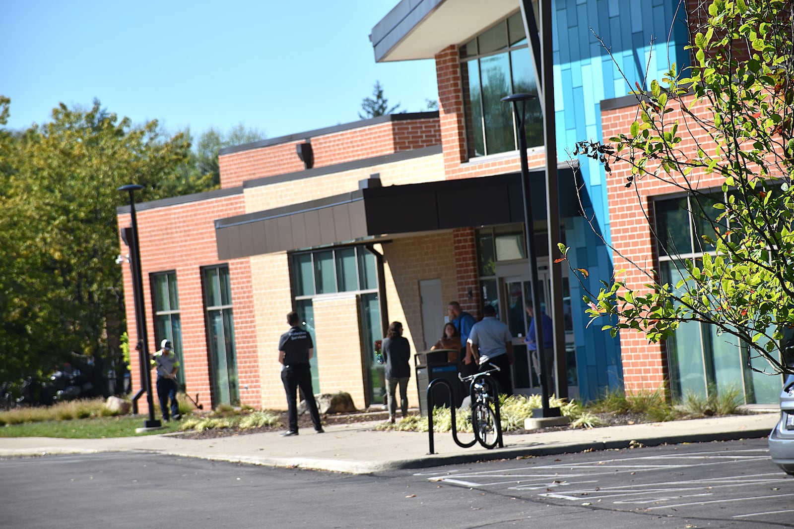 Security staff and other library employees stand outside the Dayton Metro Library Southeast Branch at 21 Watervliet Ave. after it closed down at 2:30 p.m. on a recent weekday. The library has reduced hours after a large fight broke out involving Belmont High School students. The school is next door to the library. CORNELIUS FROLIK / STAFF