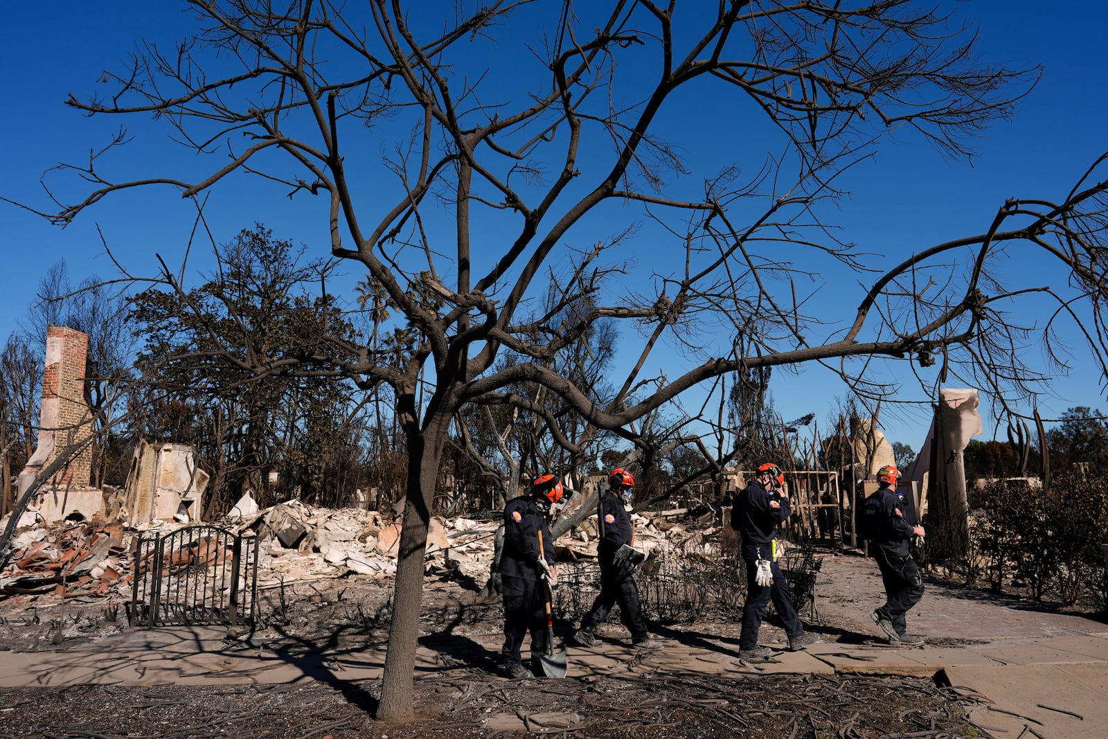 Members of a San Bernardino County Fire Department Search and Rescue crew work among the ruins of the Palisades Fire in the Pacific Palisades neighborhood of Los Angeles, Tuesday, Jan. 14, 2025. (AP Photo/Carolyn Kaster)