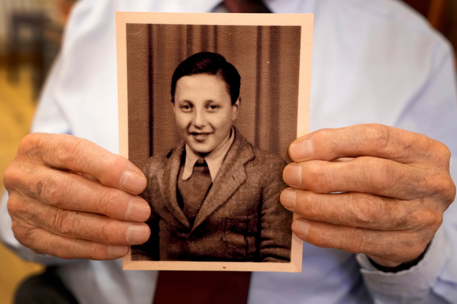 Manfred Goldberg, a Holocaust survivor displays a photograph of himself taken in Sept. 1945, as he is interviewed in London, Wednesday, Jan. 22, 2025. (AP Photo/Kirsty Wigglesworth)