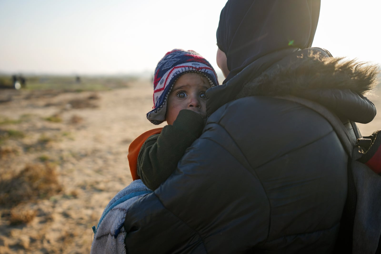 A Palestinian woman holds a baby as they return to their home in the northern Gaza Strip, following Israel's decision to allow thousands of them to go back for the first time since the early weeks of the 15-month war with Hamas, Monday, Jan. 27, 2025. (AP Photo/Abdel Kareem Hana)