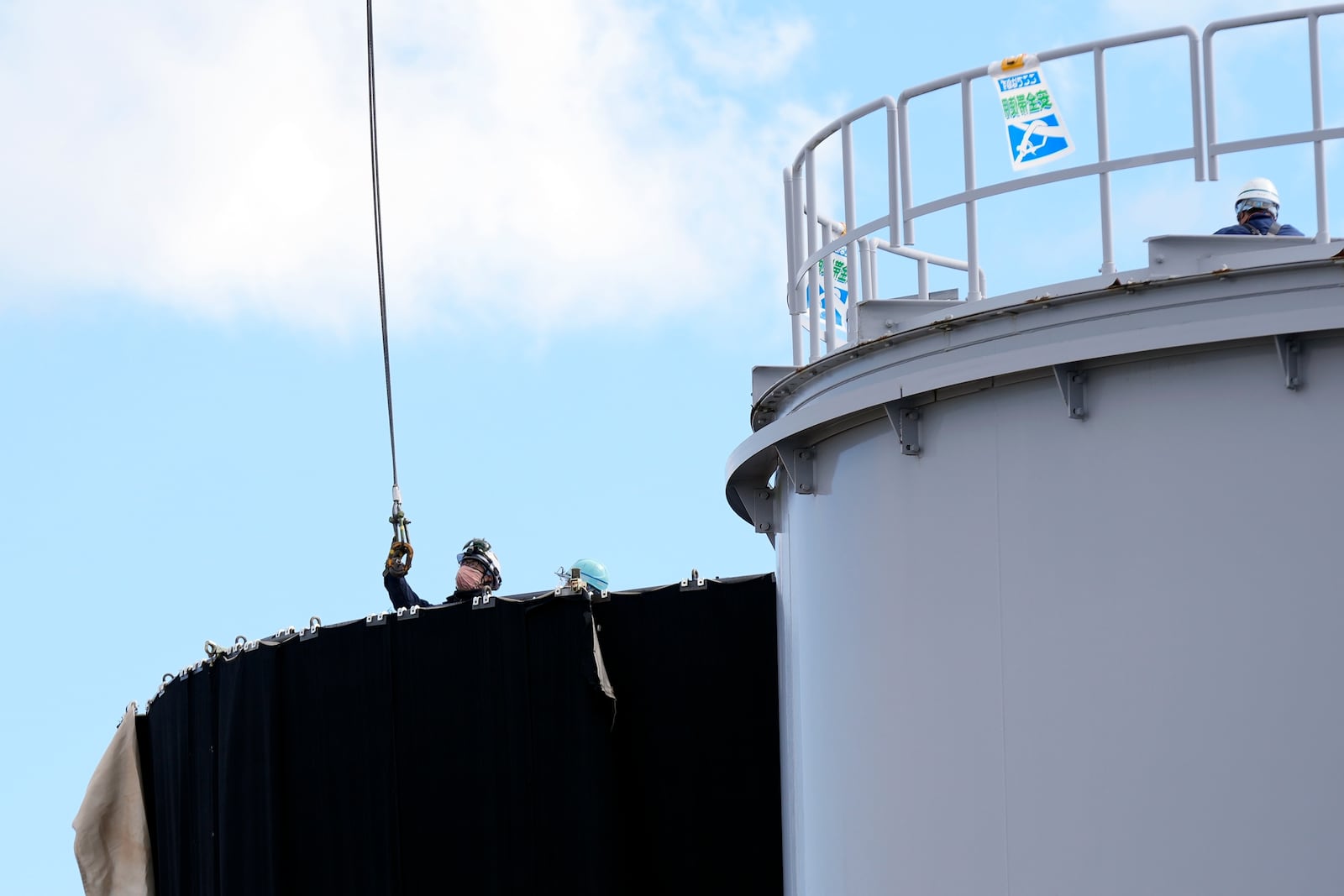 Workers carry out the dismantling work of the treated water tanks at the Fukushima Daiichi nuclear power plant, operated by Tokyo Electric Power Company Holdings (TEPCO), in Okuma town, northeastern Japan on Monday Feb. 20, 2025. (AP Photo/Eugene Hoshiko)