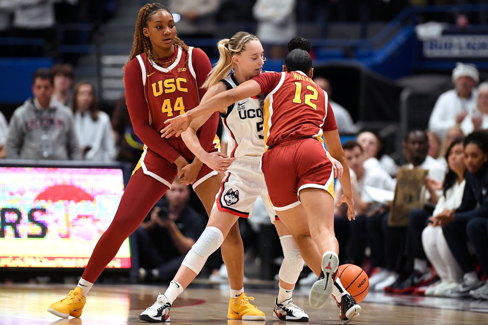 Southern California guard JuJu Watkins (12) dribbles around UConn guard Paige Bueckers (5) as Southern California forward Kiki Iriafen (44) defends in the first half of an NCAA college basketball game, Saturday, Dec. 21, 2024, in Hartford, Conn. (AP Photo/Jessica Hill)