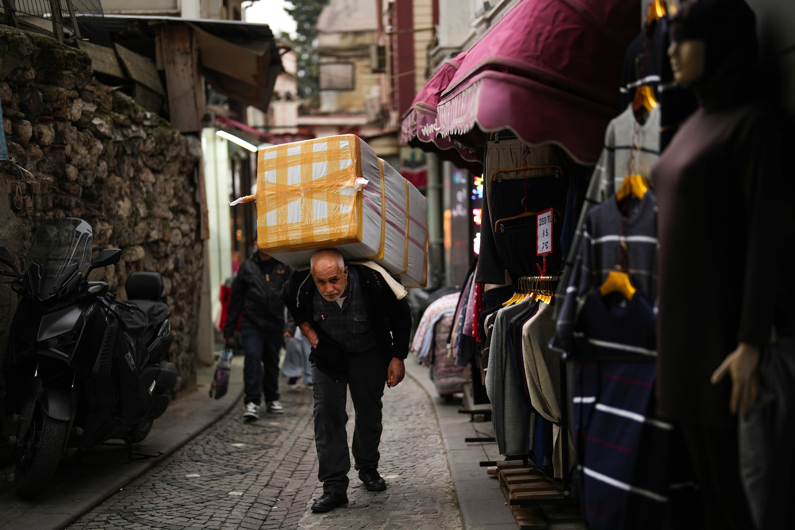 A man carries goods at Eminonu commercial area, in Istanbul, Turkey, Thursday, Dec. 26, 2024 as Turkey's central bank lowered its key interest rate by 2.5 percentage points to 47.5% carrying out its first rate cut in nearly two years as it tries to control soaring inflation. (AP Photo/Francisco Seco)