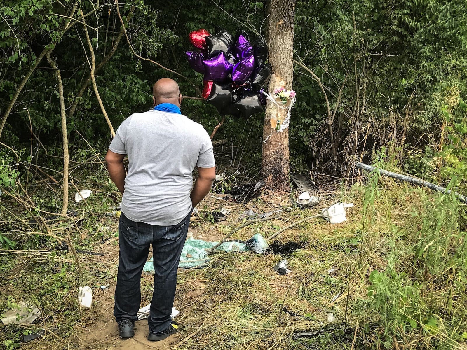 Anthony Hughes, a family member of Leah Smith, a deceased victim of a crash that also killed two others at Olive and Little Richmond roads Wednesday night, July 15, 2020, pays his respects at a roadside memorial Thursday afternoon, July 16, 2020, ahead of a planned candlelight vigil.