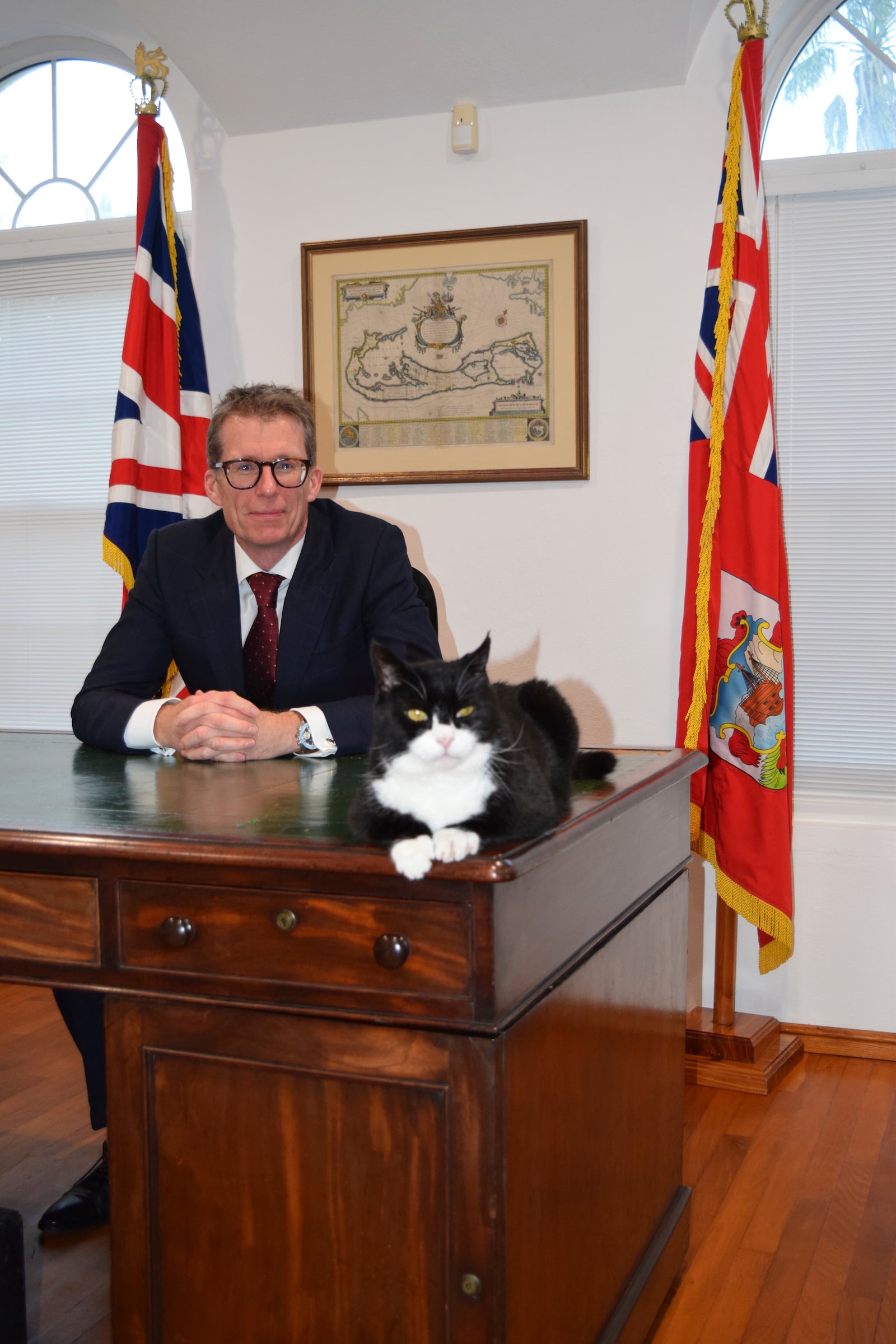 This undated handout photo shows Governor to Bermuda Andrew Murdoch, background, with former Chief Mouser to the Foreign Office Palmerston, now U.K. chief four-legged representative in Bermuda. (British Foreign Office via AP)