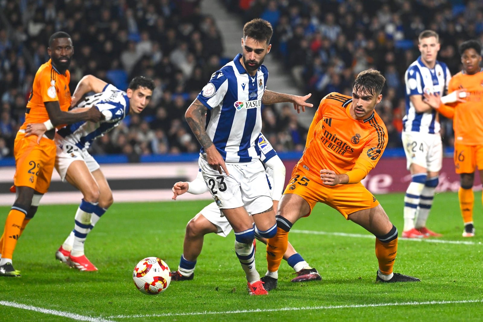 Real Sociedad's Brais Mendez, centre, challenges for the ball with Real Madrid's Raul Asencio, right, during the Spanish Copa del Rey soccer match between Real Sociedad and Real Madrid at the Reale Arena in San Sebastian, Spain, Wednesday, Feb. 26, 2025. (AP Photo/Miguel Oses)