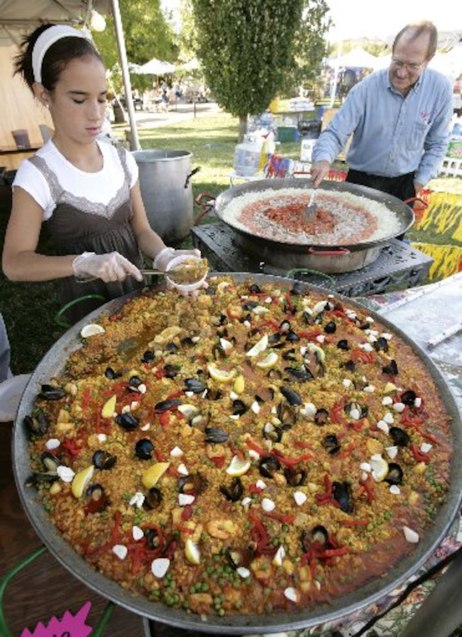 Archive photo — Anna Castro, left, served Paella as El Meson chef Mark Abbott started another paella pan featuring seafood and garlic at the 2007 Garlic Festival at Cox Arboretum Metro Park.( Photo: Ty Greenlees)