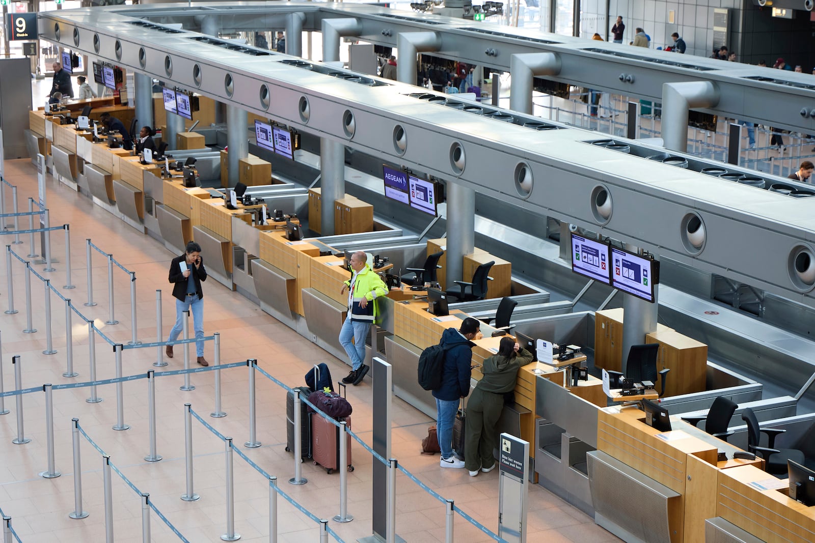 Individuals stand in front of counters at Hamburg Airport, Germany Sunday, March 9, 2025. (Georg Wendt/dpa via AP)