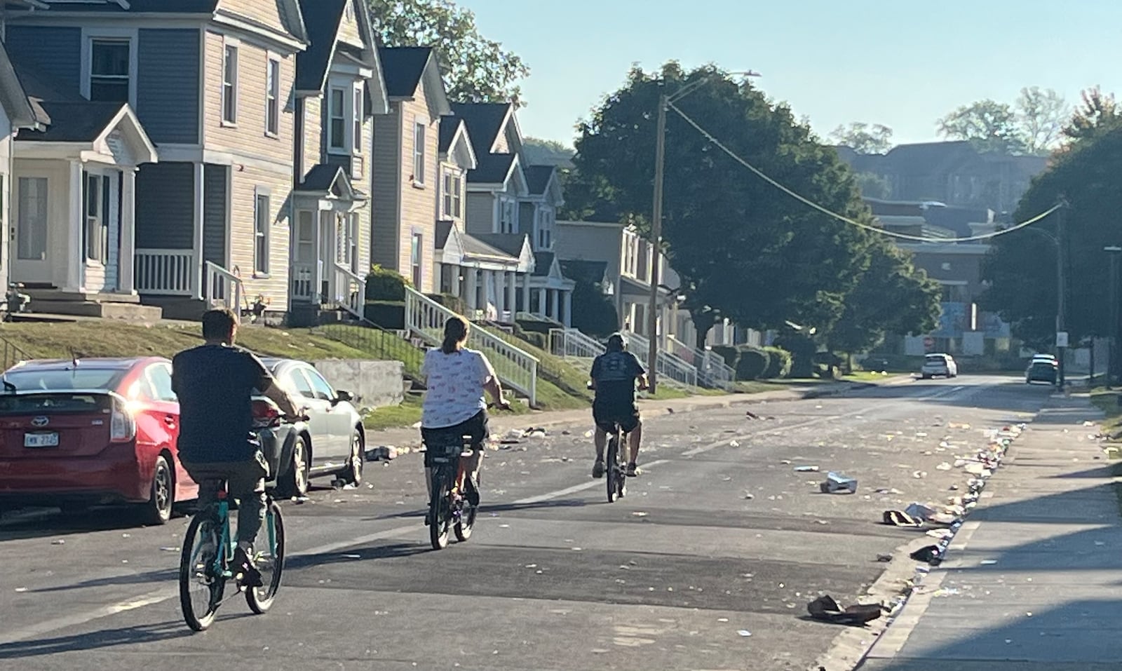 Three brave cyclists dodge a field of broken glass on Kiefaber Street near the University of Dayton on the morning of Sept. 4, 2023, after a disturbance caused a large police response the night before. JEREMY P. KELLEY / STAFF