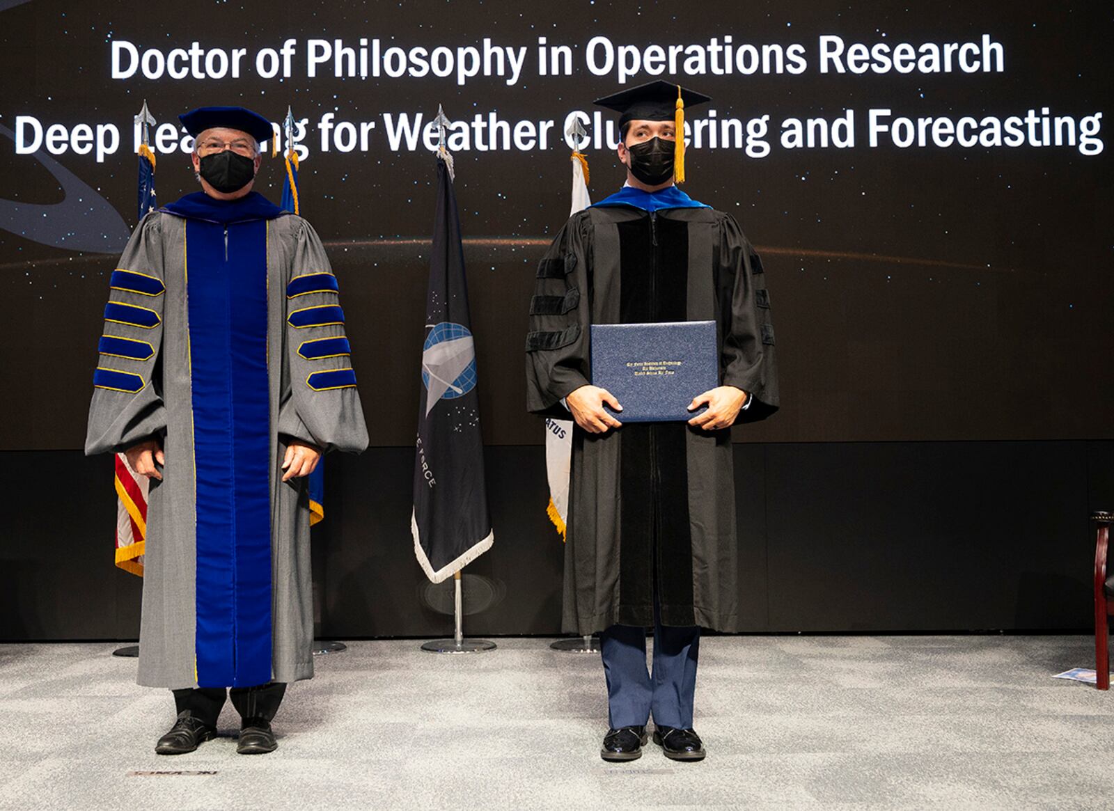 Dr. Walter Jones (left), Air Force Institute of Technology director and chancellor, stands with Capt. Nate Beveridge as he receives his doctorate of philosophy degree in operations research during a ceremony Sept. 16 at Wright-Patterson Air Force Base. U.S. AIR FORCE PHOTO/R.J. ORIEZ