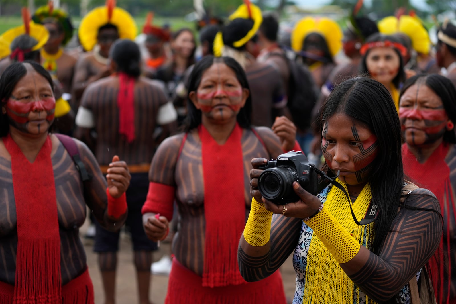 A Kayapo woman takes photos during a protest against the prospective creation of a benchmark time limit that threatens to strip some Indigenous lands, in Brasilia, Brazil, Wednesday, Oct. 30, 2024. (AP Photo/Eraldo Peres)