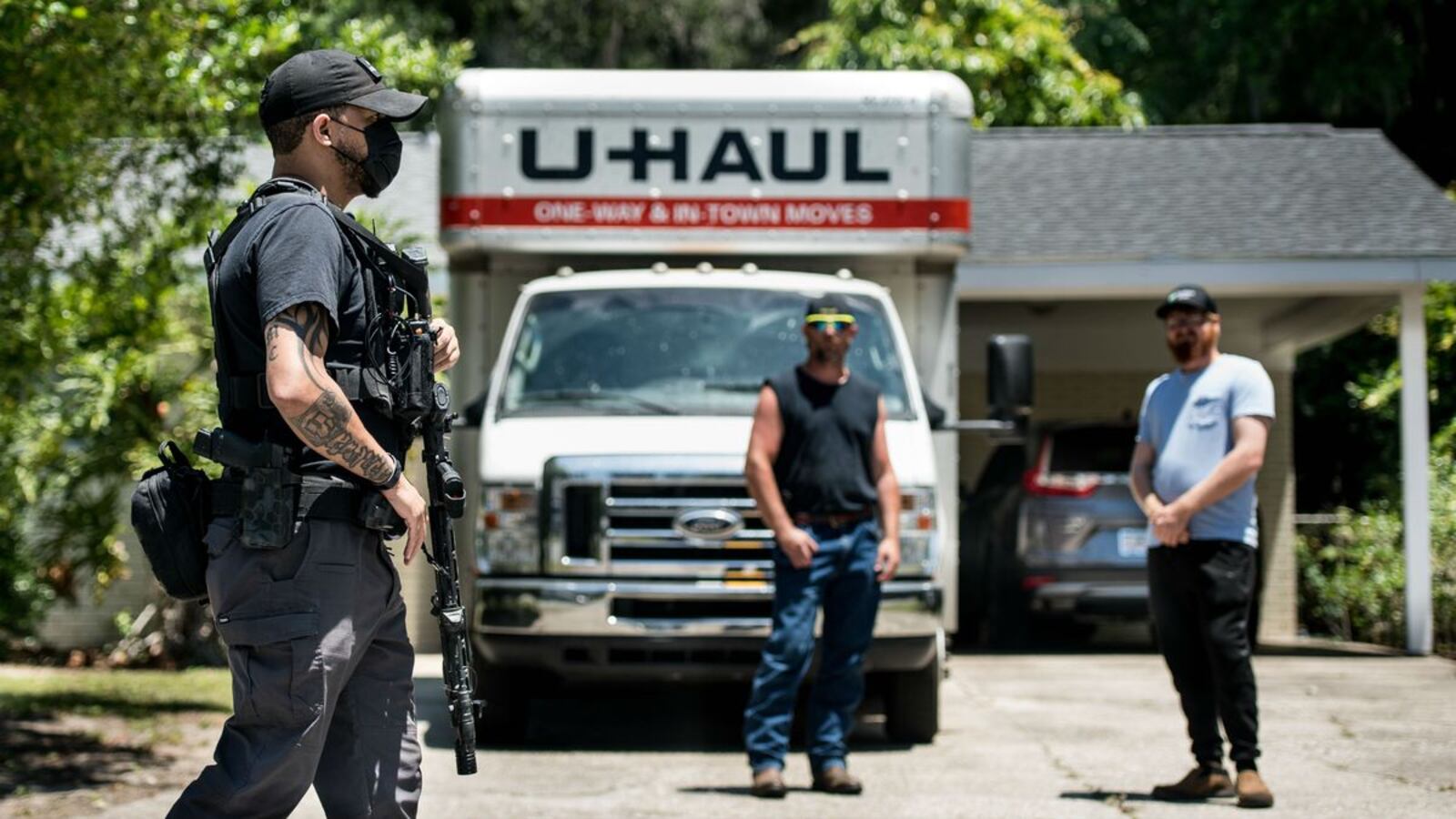 Former U.S. Marine Sgt. Sean Joseph provides armed protection for protesters in the Satilla Shores neighborhood as residents look on Friday, May 8, 2020, in Brunswick, Ga. Travis McMichaels, 34, and his father, 64-year-old Gregory McMichaels, are charged with felony murder and aggravated assault in the Feb. 23 shooting of Ahmaud Arbery, who was jogging in the predominantly white neighborhood. (Sean Rayford/Getty Images)