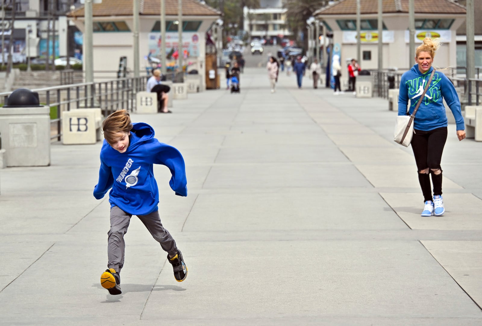 Hudson Kammarcal, 8, runs in the wind as his mother, Heidi Kammarcal, of Coeur d'Alene, Idaho, tries to keep up on the pier in Huntington Beach, Calif., Thursday, March 13, 2025, after strong storms moved through the region overnight. (Jeff Gritchen/The Orange County Register via AP)