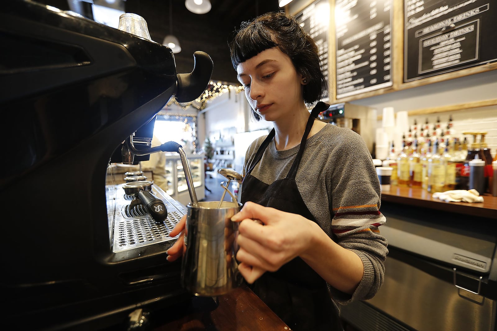 Kylee Bernhardt steams milk for a coffee drink in the Winans Chocolates and Coffees in downtown Springfield. BILL LACKEY/STAFF