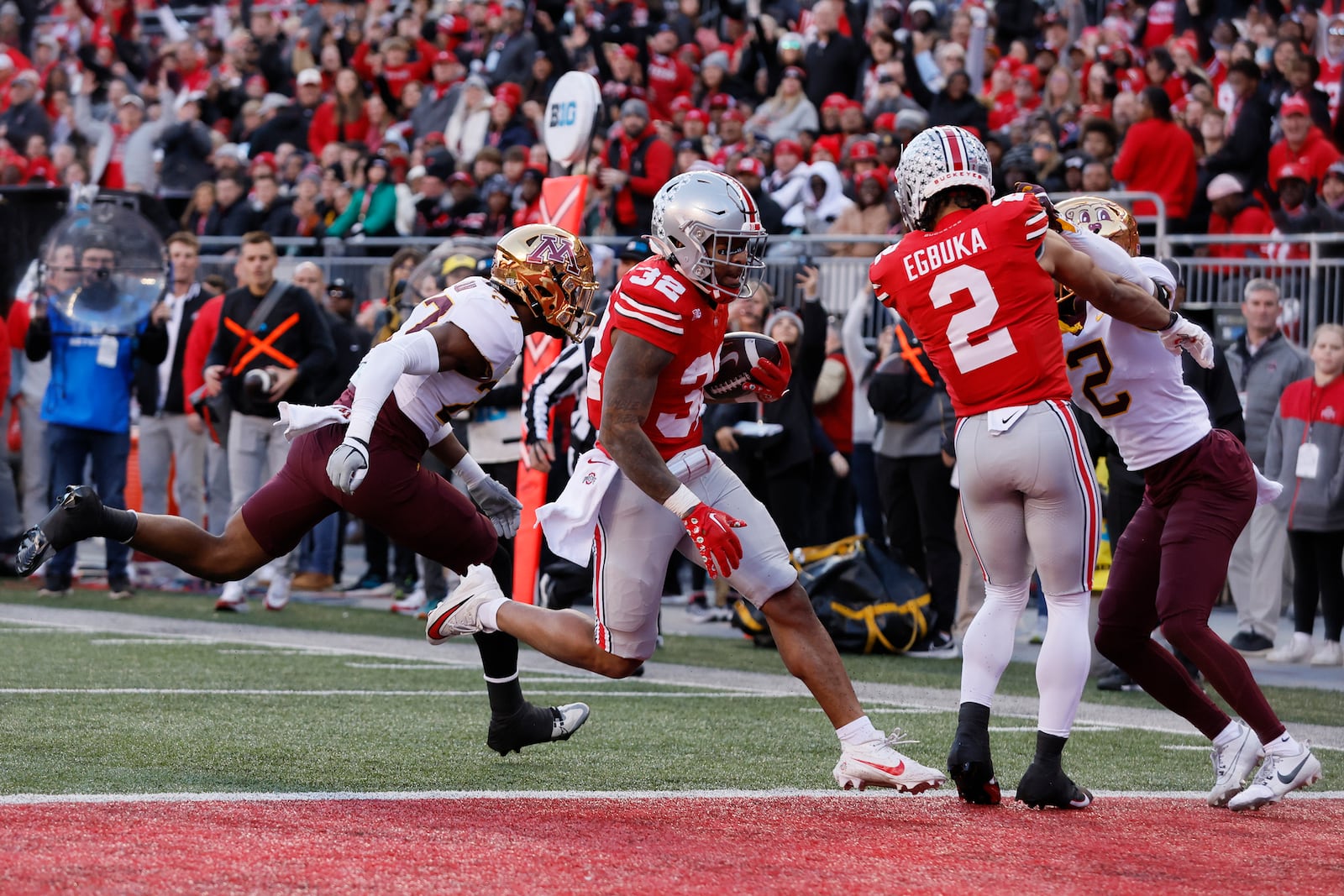 Ohio State running back TreVeyon Henderson (32), center, scores a touchdown past Minnesota defensive back Tyler Nubin, left, as Ohio state receiver Emeka Egbuka (2) blocks for him during the first half of an NCAA college football game Saturday, Nov. 18, 2023, in Columbus, Ohio. (AP Photo/Jay LaPrete)