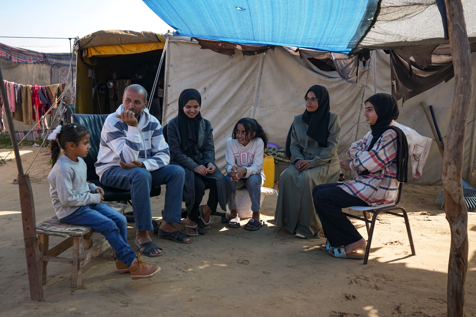 Members of the Abu Jarad family, who were displaced by the Israeli bombardment of the Gaza Strip, gather in front of their tent at a camp for displaced Palestinians in the Muwasi area, southern Gaza Strip, Saturday, Jan. 18, 2025. (AP Photo/Abdel Kareem Hana)