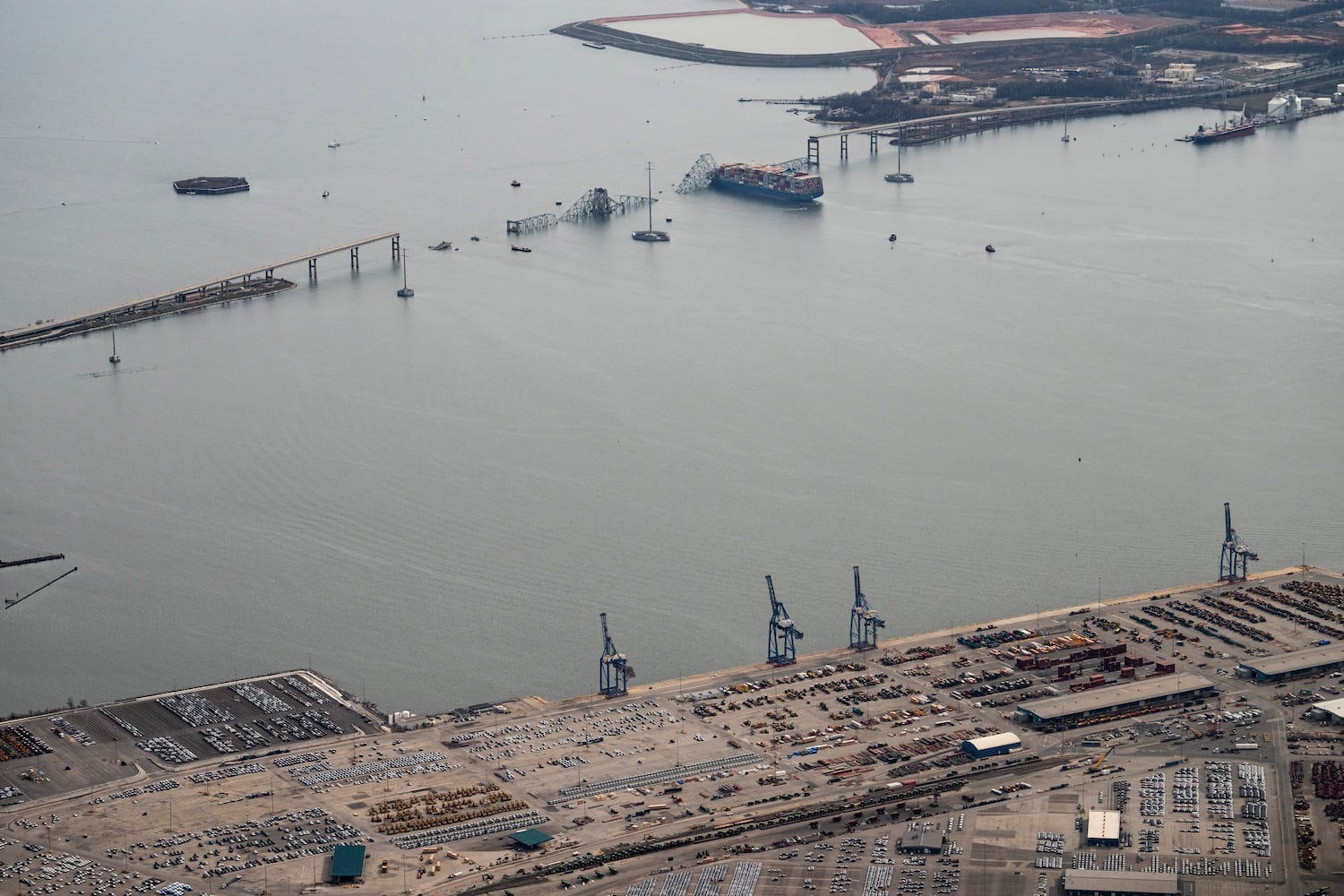 
                        An aerial view of the Dali container ship with a collapsed section of the Francis Scott Key Bridge across its bow after it collided with the bridge early Tuesday morning and the Dundalk Marine Terminal in the foreground in Baltimore, Md., on Tuesday, March 26, 2024. Six construction workers who had been fixing potholes on the Francis Scott Key Bridge remained missing as divers and other emergency workers on boats and helicopters continued to search for them. Two others had been rescued. (Erin Schaff/The New York Times)
                      