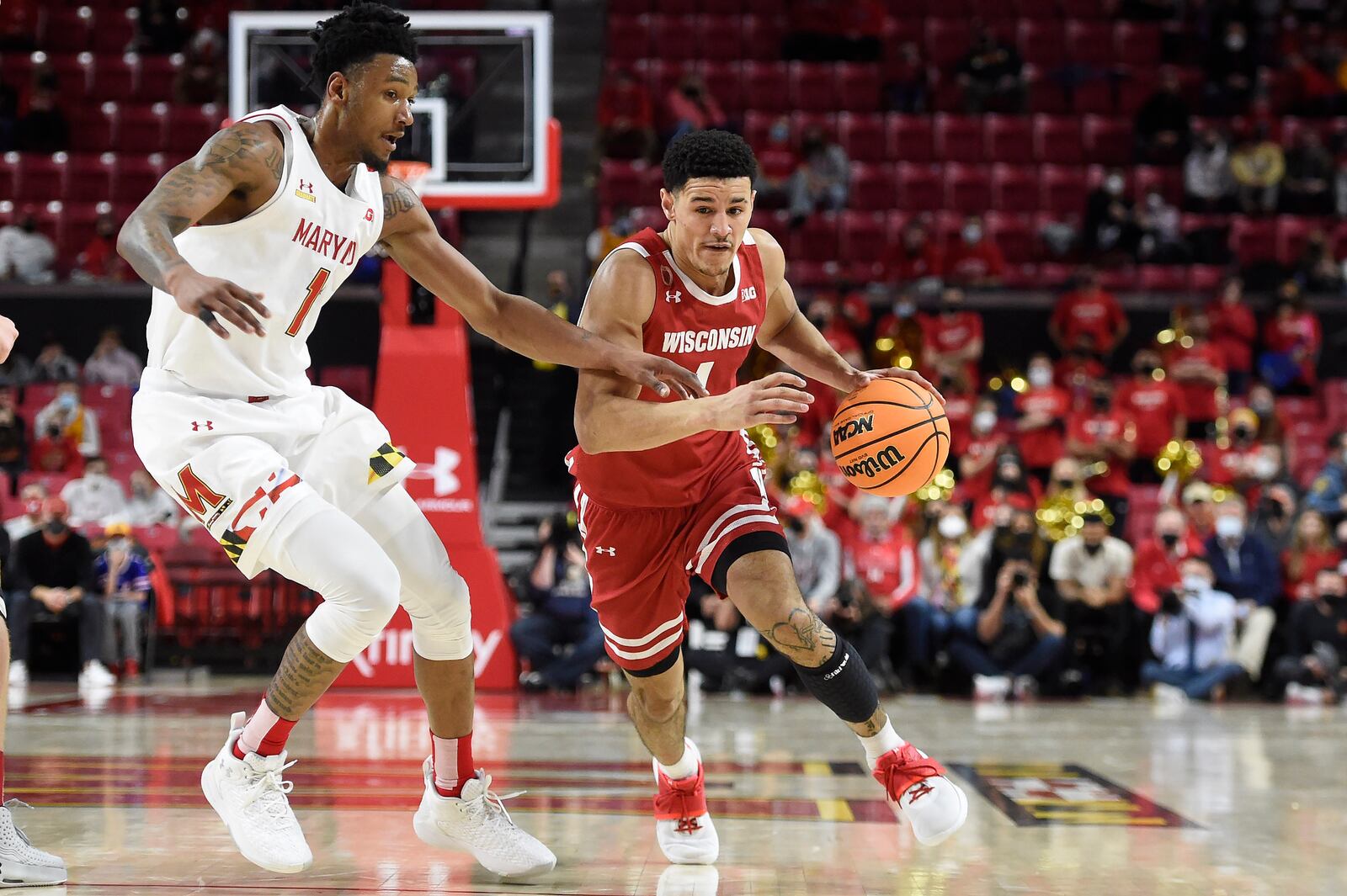 Wisconsin's Johnny Davis, right, drives as Maryland 's Xavier Green pursues, left, in the first half of an NCAA college basketball game on Sunday, Jan. 9, 2022, in College Park, Md. (AP Photo/Gail Burton)