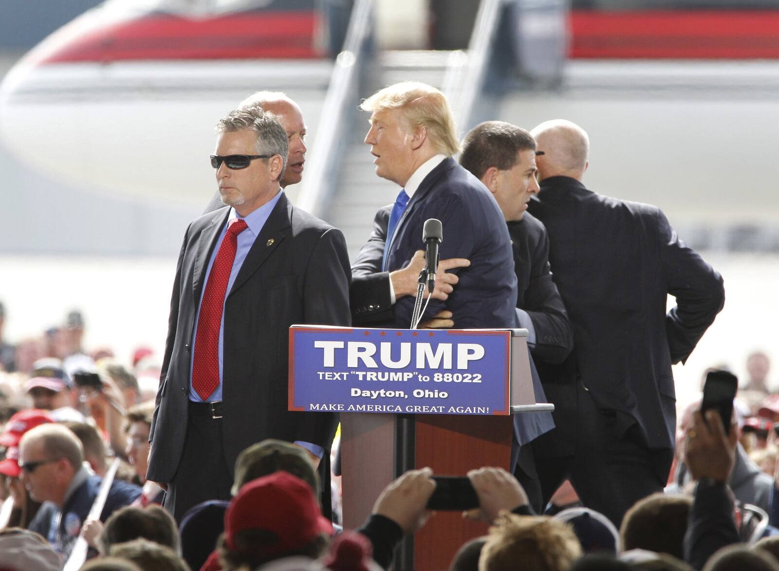 Security surrounds Republican presidential candidate Donald Trump after a man tried to rush the stage during a rally in front of thousands at Wright Brothers Aero Saturday. Thomas Dimassimo, 32, of Fairborn, was arrested at the Donald Trump rally on suspicion of disorderly conduct and inducing panic, Montgomery County Sheriff Phil Plummer has confirmed. LISA POWELL / STAFF