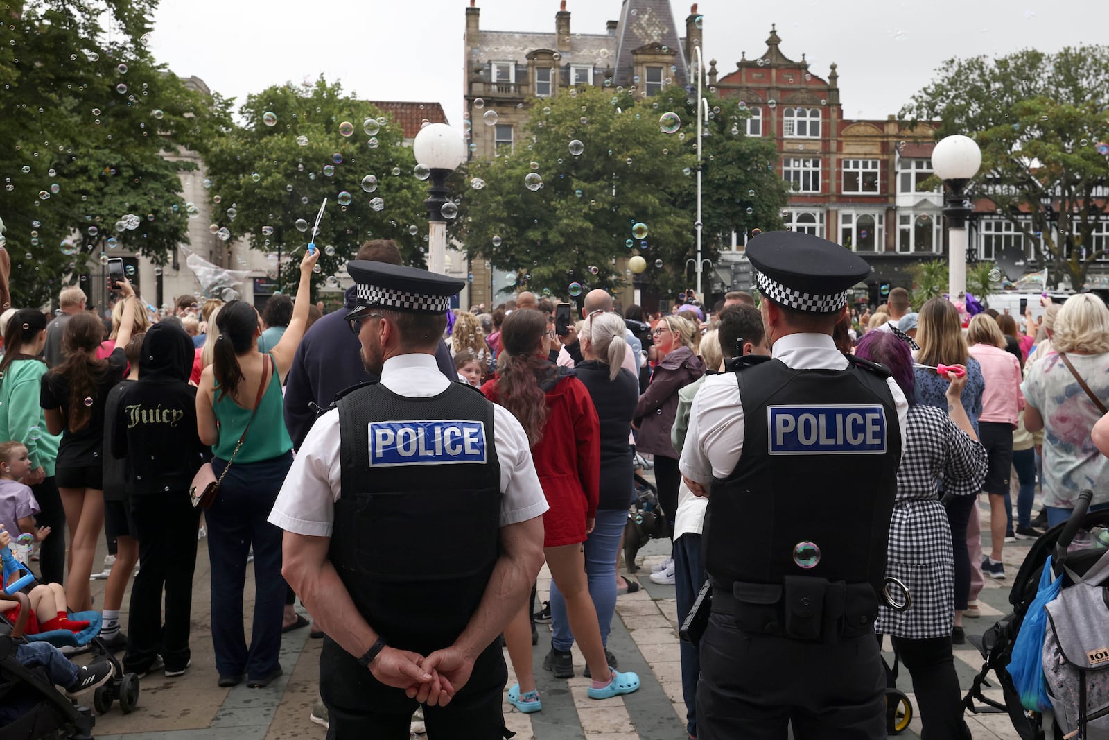 FILE - Police officers watch members of the public outside the Town Hall in Southport, England, Aug. 5, 2024 after three young girls were killed in a knife attack at a Taylor Swift-themed holiday club the week before. (AP Photo/Darren Staples, File)