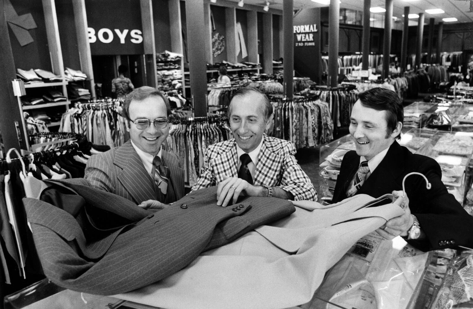 Larry Zusman (center), president; Ronald Decuir (left) and Gene Dyrdek (right) look at jackets in the newly remodeled Price Stores building in downtown Dayton in 1976. STAFF FILE PHOTO