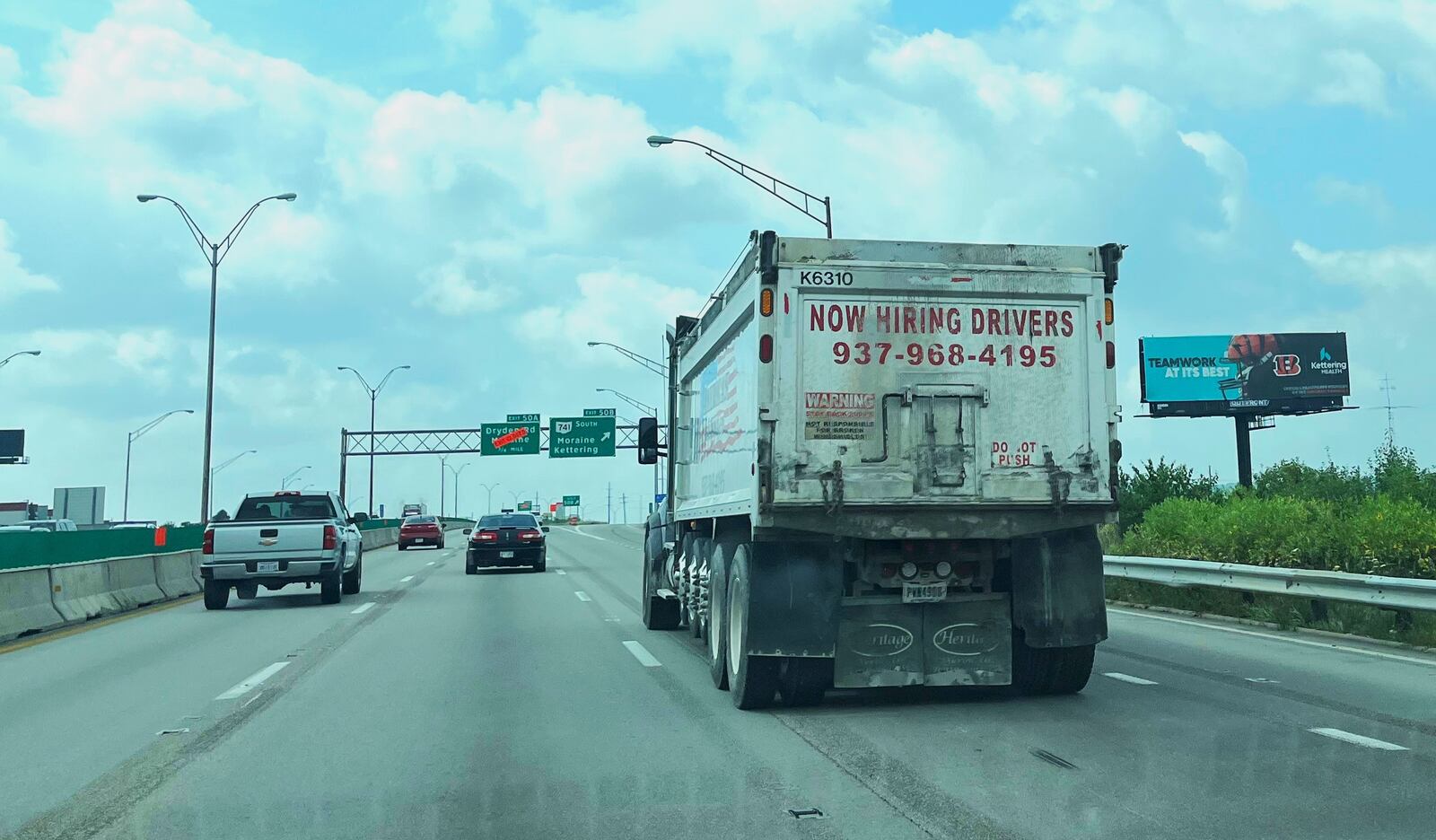 A truck on a freeway in Dayton has a "now hiring drivers" ad on the back of the vehicle. CORNELIUS FROLIK / STAFF