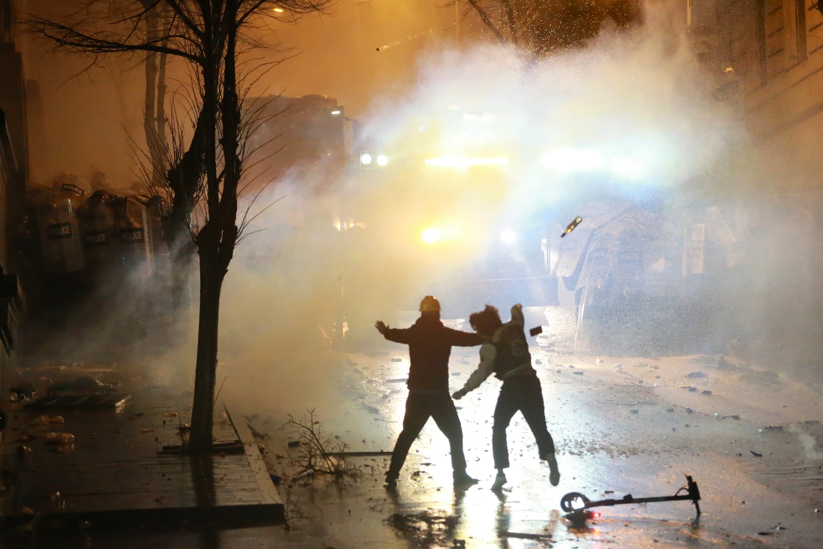 A demonstrator throws a bottle toward police as protesters rally against the government's decision to suspend negotiations on joining the European Union for four years, outside the parliament's building in Tbilisi, Georgia, early Sunday, Dec. 1, 2024. (AP Photo/Zurab Tsertsvadze)