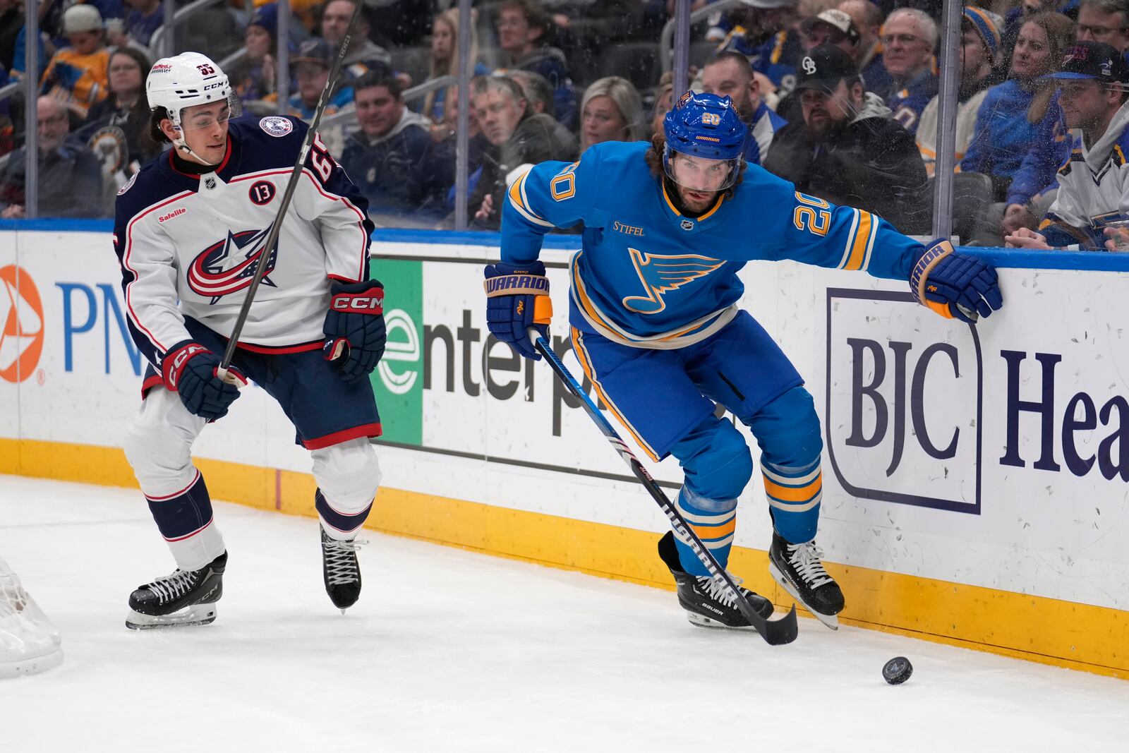 Columbus Blue Jackets' Luca Del Bel Belluz (65) and St. Louis Blues' Brandon Saad (20) chase after a loose puck during the second period of an NHL hockey game Saturday, Jan. 11, 2025, in St. Louis. (AP Photo/Jeff Roberson)