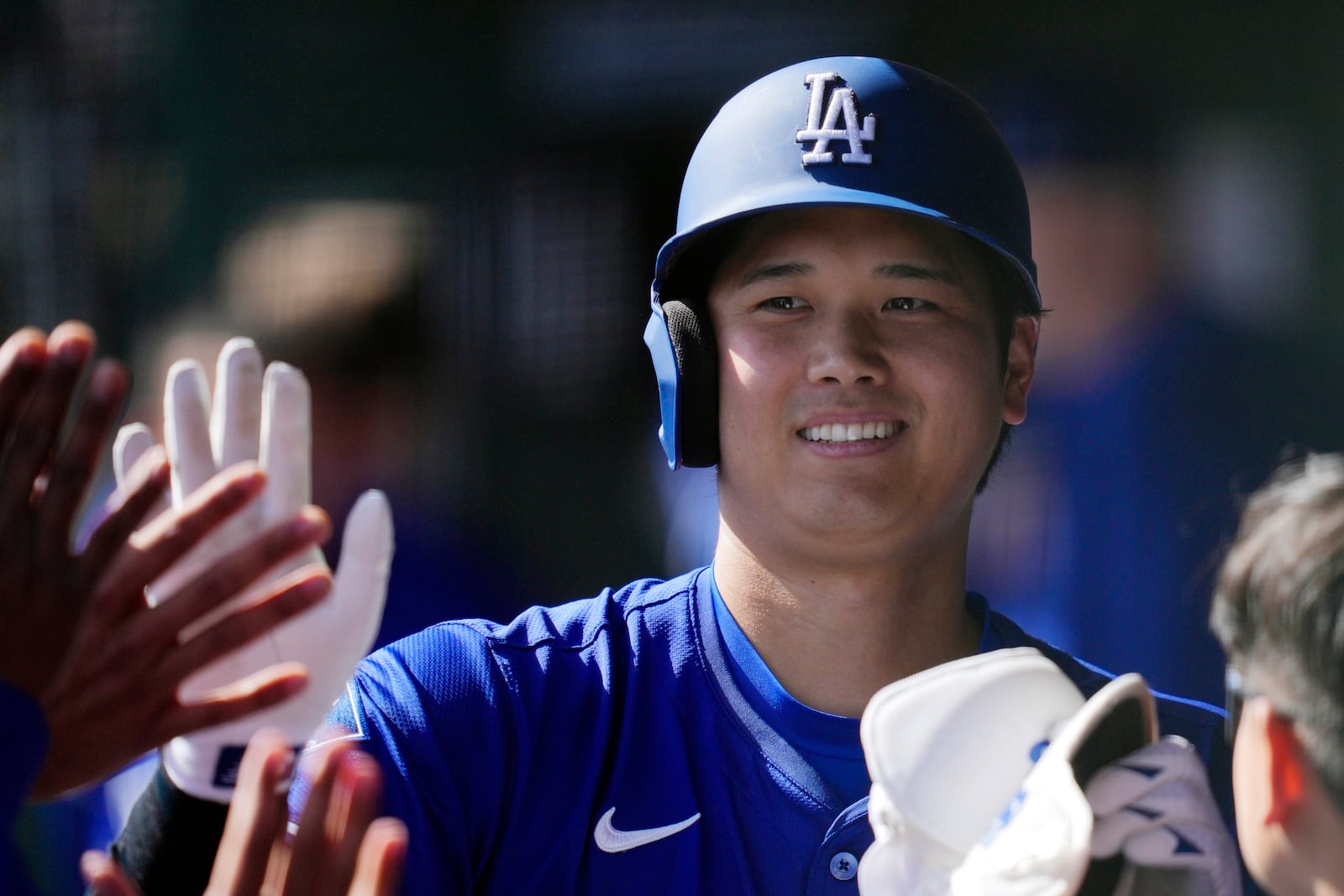 Los Angeles Dodgers' Shohei Ohtani, of Japan, smiles as he celebrates in the dugout after hitting a single against the Texas Rangers and being replaced by a pinch runner in the sixth inning of a spring training baseball game Thursday, March 6, 2025, in Phoenix. (AP Photo/Ross D. Franklin)