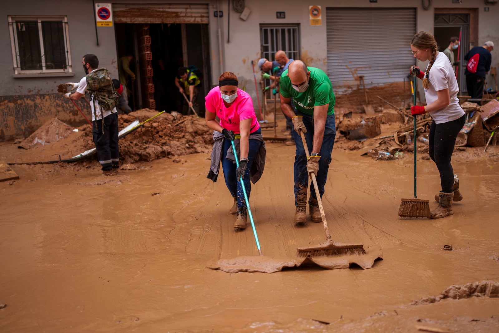 People clean the street of mud in an area affected by floods in Valencia, Spain, Saturday, Nov. 2, 2024. (AP Photo/Manu Fernandez)