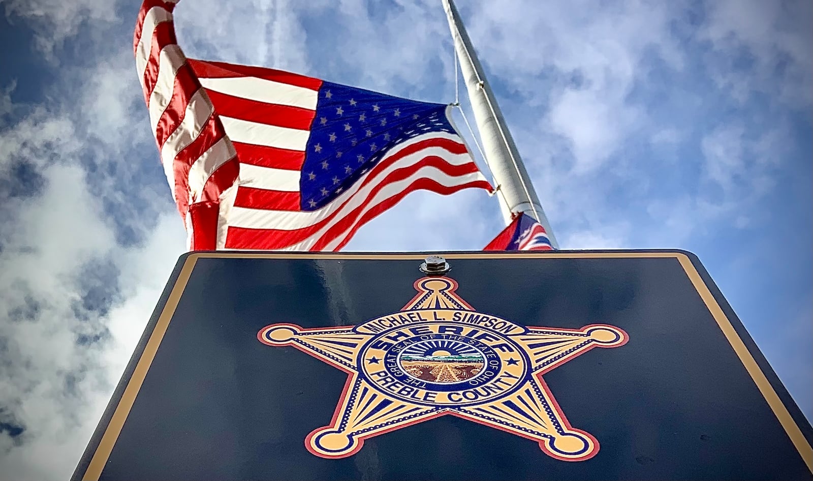 The American flag flies at half staff over the Preble County Sheriff's Office Monday, Dec. 18, 2018, after Deputy Joshua Hamilton was killed in an early morning head-on crash in his cruiser on state Route 503 between Gratis and West Alexandria. MARSHALL GORBY\STAFF