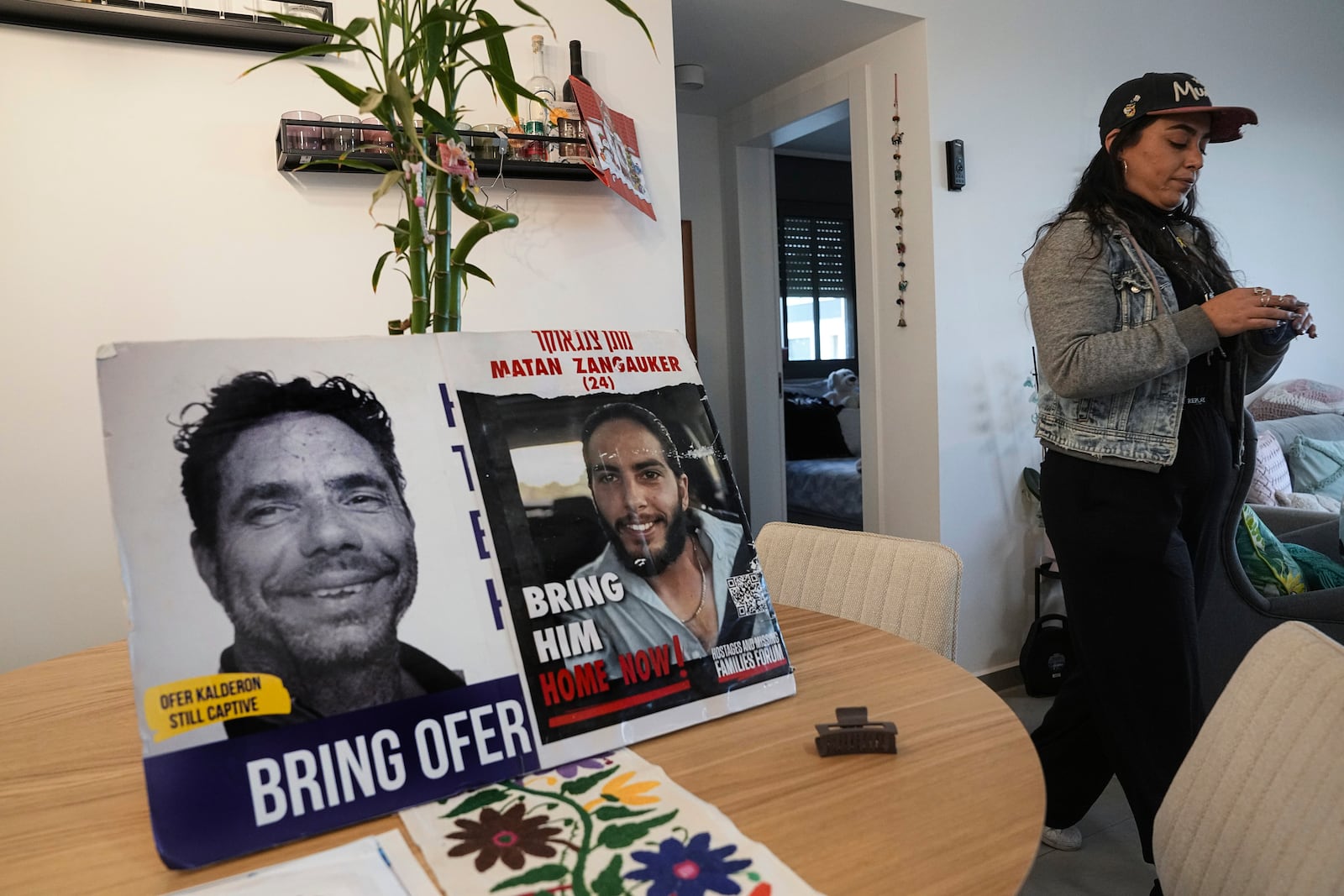 Released hostage Ilana Gritzewsky stands in her apartment in Kiryat Gat, Israel, on Sunday, Dec. 15, 2024, near photos of her boyfriend, Matan Zangauker, who is being held hostage by Hamas in the Gaza Strip. (AP Photo/Tsafrir Abayov)