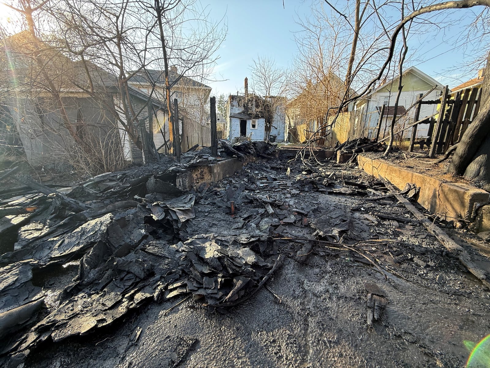 Charred debris behind a home at 43 Victor Ave. in northwest Dayton was still smoking on Friday morning hours after crews responded to a report of a garage fire. CORNELIUS FROLIK / STAFF