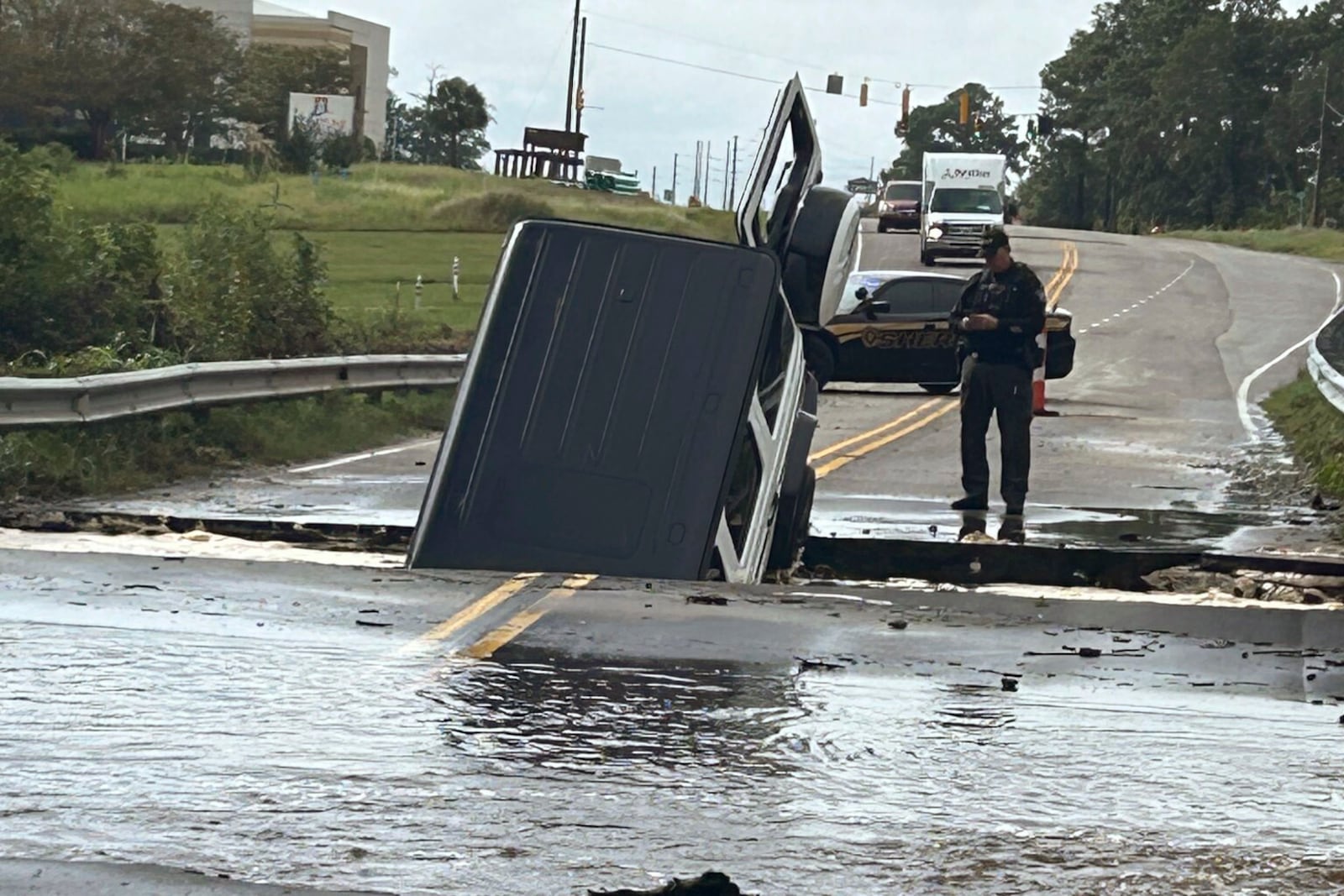 FILE - This photo provided by Brunswick County Sheriff's Office shows a police officer checking on a vehicle that fell into a sinkhole on a highway in Brunswick County, N.C., after a storm dropped historic amounts of rain, Monday, Sept. 16, 2024. (Brunswick County Sheriff's Office via AP, File)