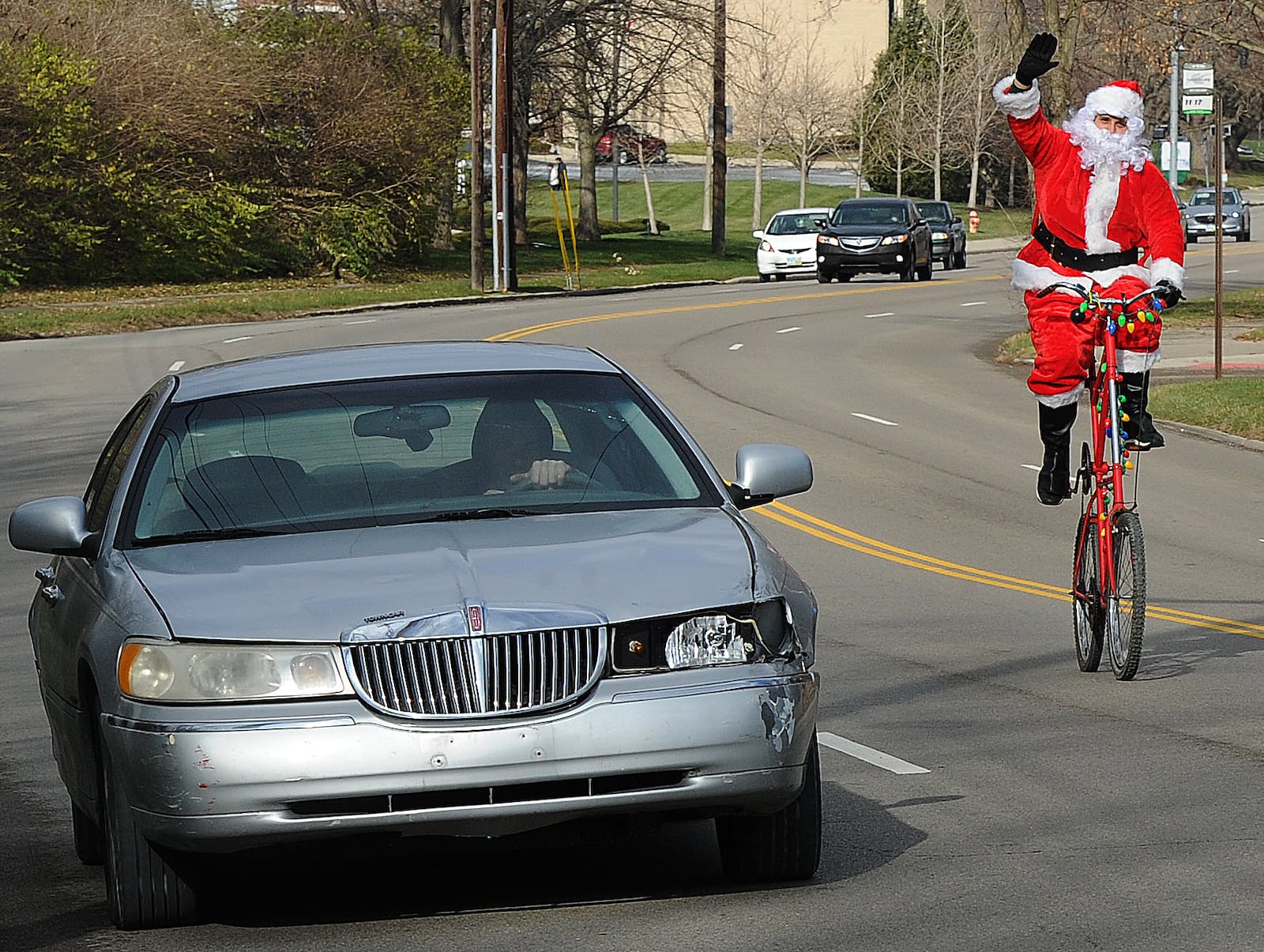 A man dressed as Santa Claus rides a double-decker bicycle as he waves and shouts "Merry Christmas" on Friday, Dec. 18, 2020, in Dayton. He is shown here on Far Hills Avenue. MARSHALL GORBY\STAFF