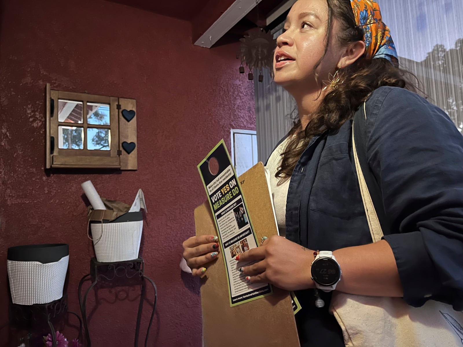 Tania Ortega, 27, speaks with a Santa Ana, Calif. resident on Wednesday, Oct. 23, 2024, about Measure DD, which would allow noncitizens to vote in local elections. (AP Photo/Jaimie Ding)