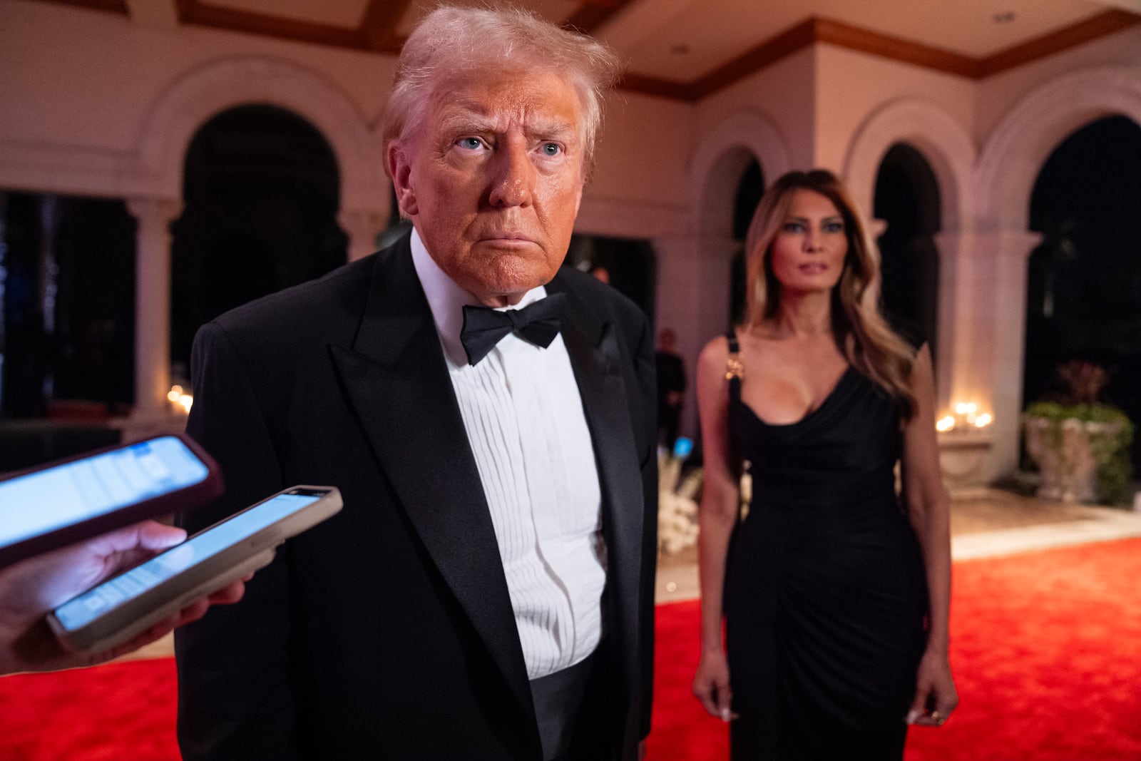 FILE - President-elect Donald Trump, accompanied by his wife Melania, listens to a reporter's question, before a New Year's Eve party at Mar-a-Lago in Palm Beach, Fla., Dec. 31, 2024. (AP Photo/Evan Vucci, File)