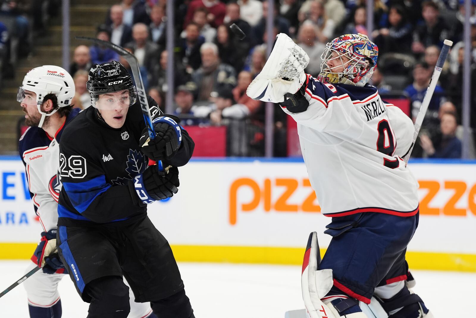 Columbus Blue Jackets goaltender Elvis Merzlikins (90) reaches for the puck in front of Toronto Maple Leafs' Pontus Holmberg (29) during second period NHL hockey action in Toronto on Wednesday, January 22, 2025. (Frank Gunn/The Canadian Press via AP)