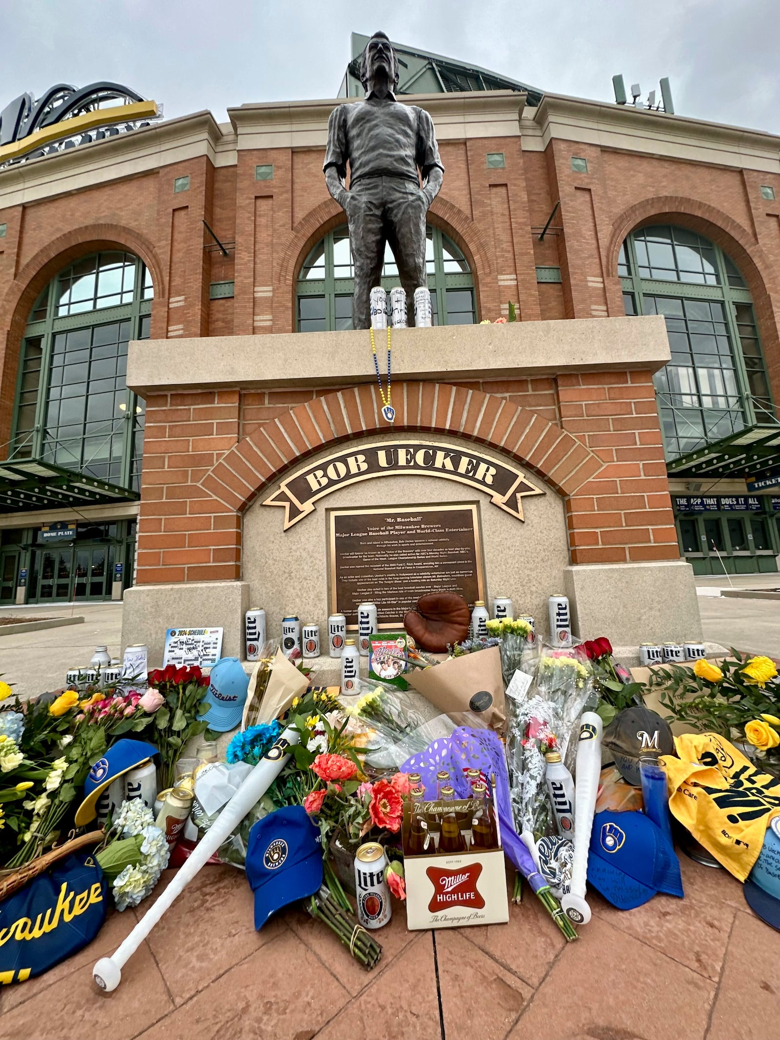 Items are left at the base of a statue of Bob Uecker outside American Family Field in Milwaukee, Thursday, Jan. 16, 2025. (AP Photo/Steve Megargee)