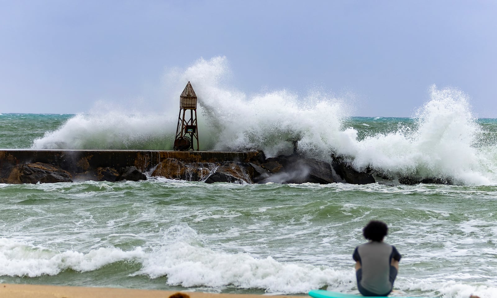 A surfer looks the waves crashing against the jetty at the Bal Harbour Lighthouse on Tuesday, Nov. 5, 2024, in Bal Harbour, Fla. (David Santiago/Miami Herald via AP)