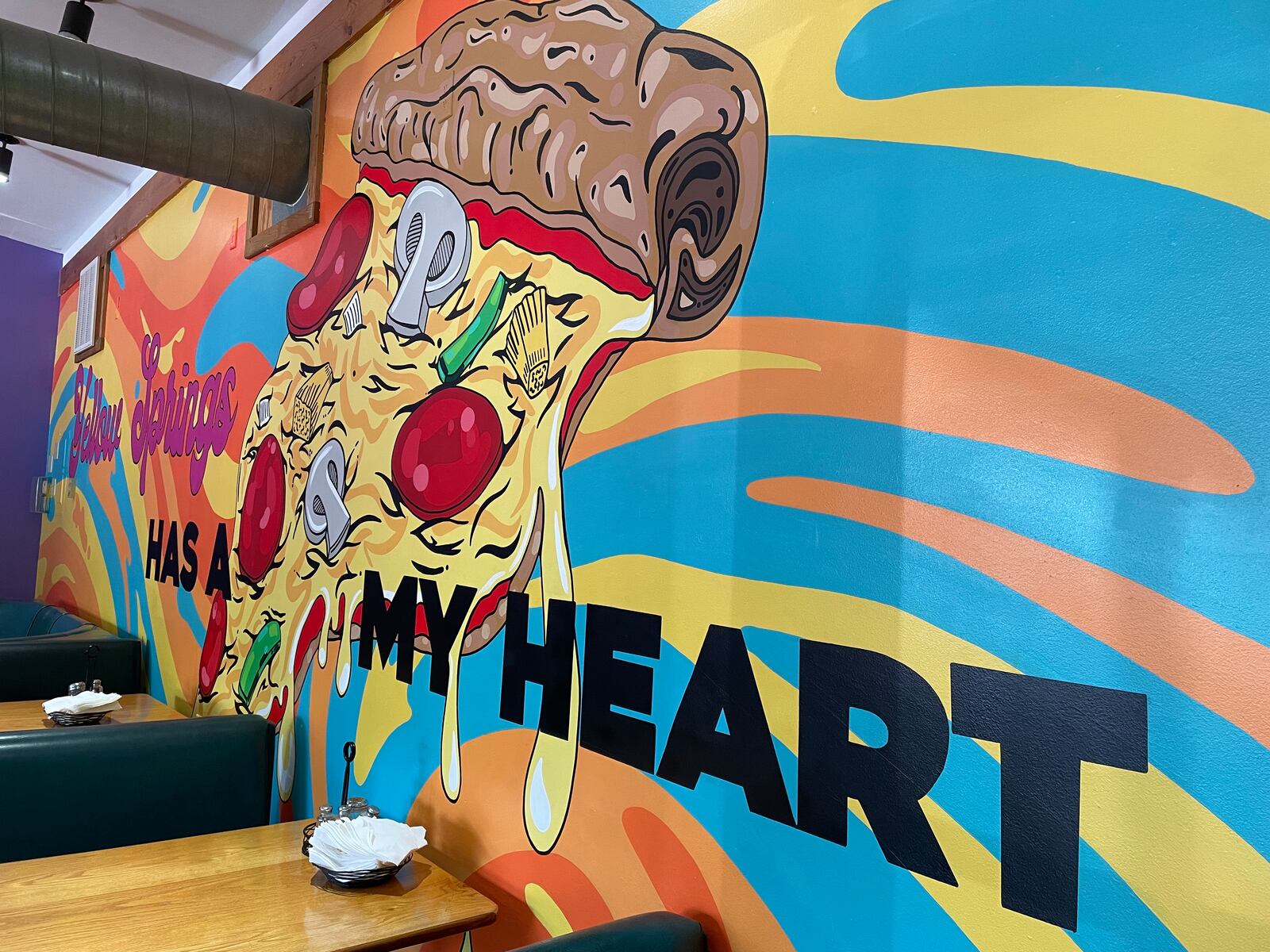 Dayton-area artist Chloé Chicarelli has put her love for Yellow Springs and Ha Ha Pizza on display through a new mural inside the pizza shop. NATALIE JONES/STAFF