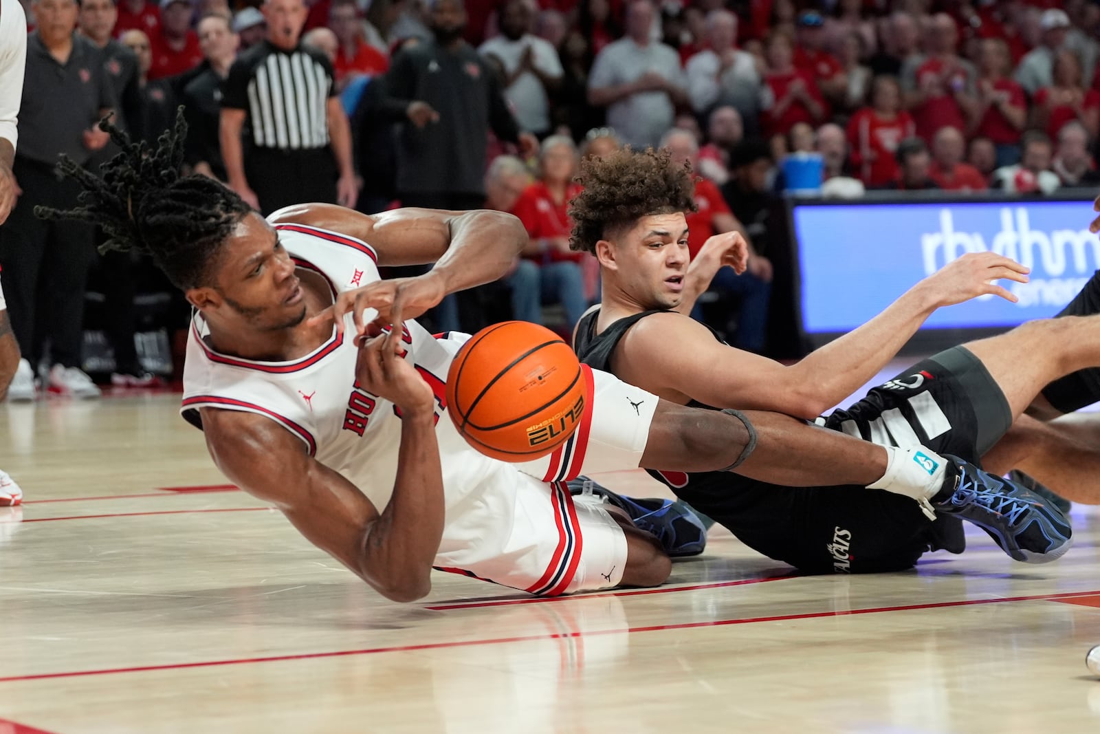 Houston's Joseph Tugler, left, and Cincinnati's Dan Skillings Jr. battle for a loose ball during the first half of an NCAA college basketball game Saturday, March 1, 2025, in Houston. (AP Photo/David J. Phillip)