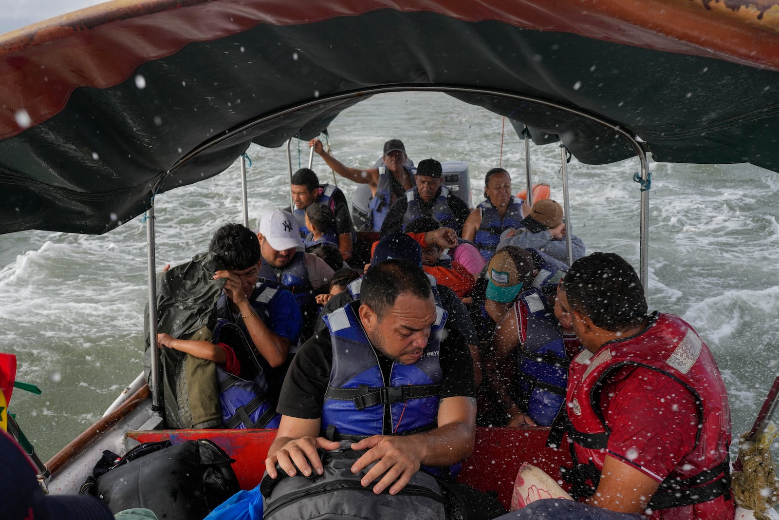 Luis Sanchez, center, sits with other Venezuelan migrants on a boat leaving Gardi Sugdub on Panama's Caribbean coast, Sunday, Feb. 23, 2025, after giving up hopes of reaching the U.S. while in southern Mexico amid President Trump's crackdown on migration. (AP Photo/Matias Delacroix)